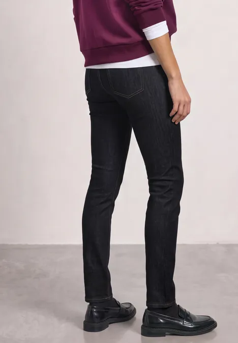 Jean taille moyenne, coupe Slim Leg, style décontracté Deep Rinse Washed Rückansicht einer Person in schwarzer Skinny-Jeans, schwarzen Schuhen und violettem Oberteil.