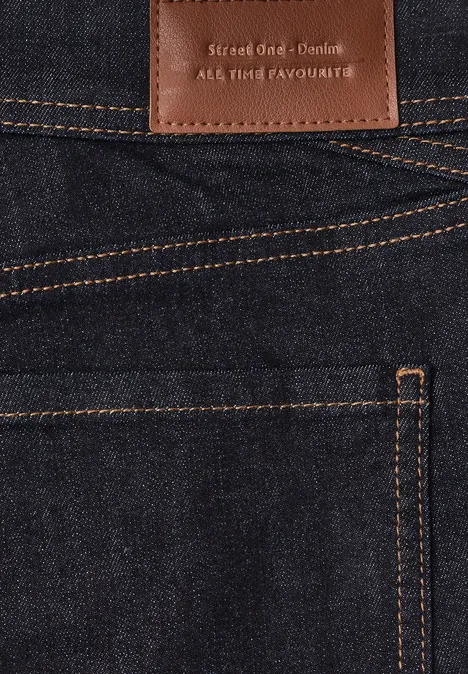 Jean taille moyenne, coupe Slim Leg, style décontracté Deep Rinse Washed Detailaufnahme einer dunkelblauen Jeans mit kontrastierenden orangen Nähten und Lederlabel über der Gesäßtasche.