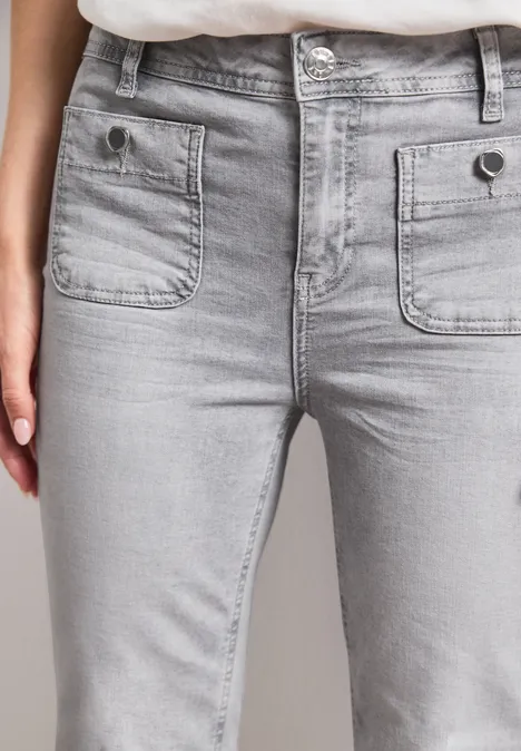 Frontansicht einer Person in hellgrauen Jeans mit zwei aufgesetzten Taschen und Knöpfen
