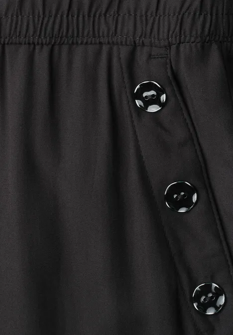 Schwarze Hose mit elastischem Bund und seitlicher Knopfleiste mit drei Knöpfen.