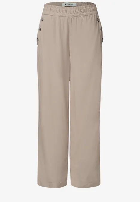 Bequeme, weit geschnittene, beige Hose mit elastischem Bund und seitlichen Knopfleisten.