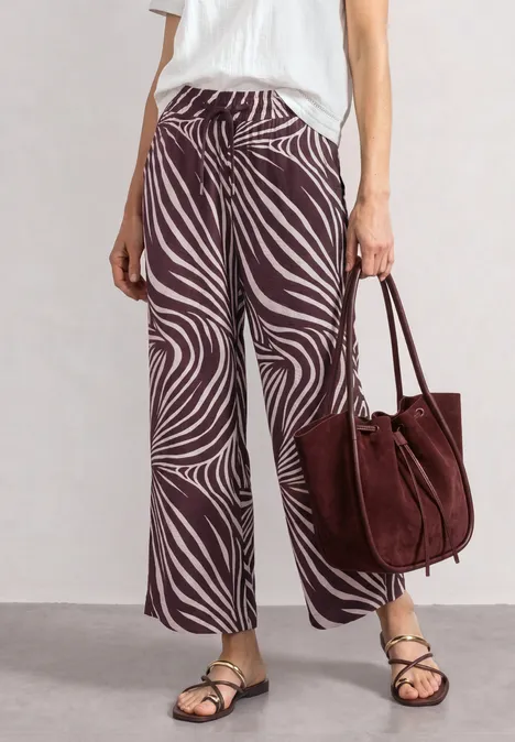 Wide Leg Hose mit Print und Gallonstreifen rustic rouge Modisches Outfit: weite Zebrahose, flache Riemchensandalen und große bordeauxrote Wildledertasche.