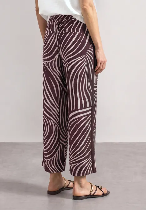 Wide Leg Hose mit Print und Gallonstreifen rustic rouge Breite Hose mit braun-beigem Zebra-Muster, gerade geschnitten, knöchellang, kombiniert mit Sandalen.