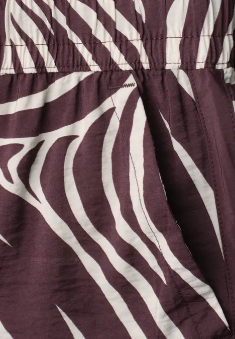 Wide Leg Hose mit Print und Gallonstreifen rustic rouge Nahaufnahme von braun-weiß gestreiftem Stoff mit Zebra-Muster.