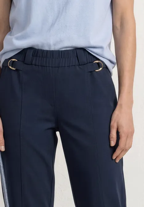 Dunkelblaue Damenhose mit elastischem Bund und silbernen Ringen, kombiniert mit hellblauem Oberteil.