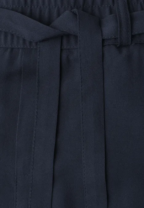 Nahaufnahme einer dunkelblauen Hose mit elastischem Bund und Stoffbindegürtel.