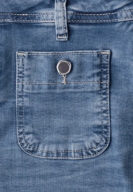 Blauer Jeansstoff mit kleiner aufgesetzter Tasche, in der ein silberner Schlüsselring steckt.