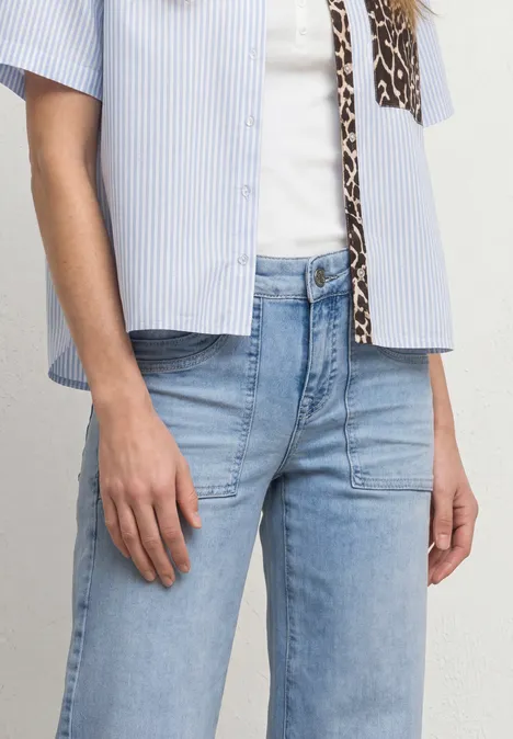 Mid Waist Jeans Culotte im Loose Fit Ultra Bleached Random Wash Eine Person trägt hellblaue Jeans und ein gestreiftes Kurzarmhemd über einem weißen Top.