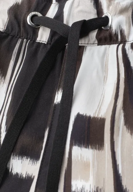 Nahaufnahme eines Bekleidungsstücks mit schwarz-weißen Pinselstrichen und schwarzem Kordelzug.