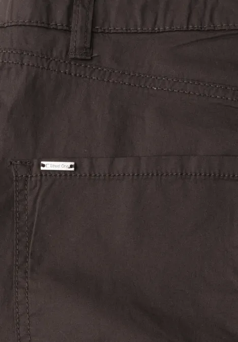 Nahaufnahme einer dunkelbraunen Stoffhose mit Tasche und kleinem Metall-Label.