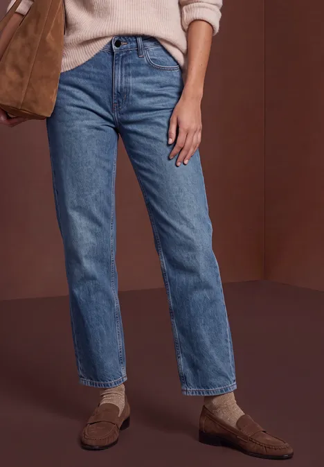 Mid Waist Straight Leg Jeans im Casual Fit Dark blue washed Eine Person trägt gerade geschnittene blaue Jeans, weiße Socken und braune Loafers.