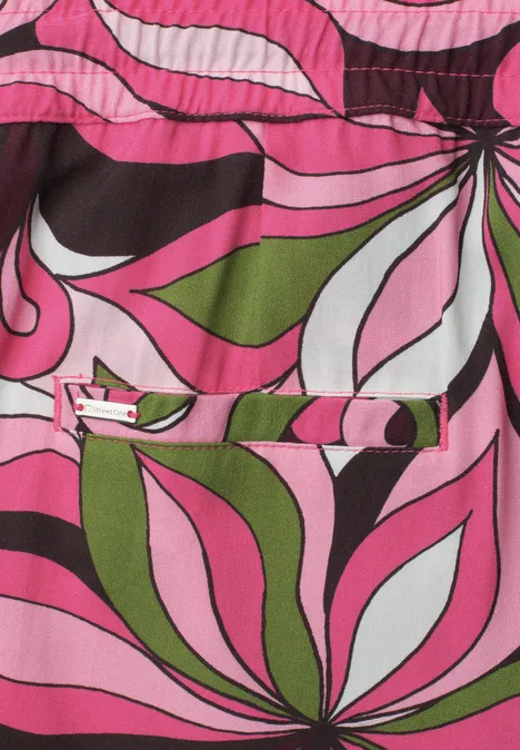 Buntes, psychedelisches Blumenmuster in Pink, Grün, Weiß und Schwarz auf Stoff.