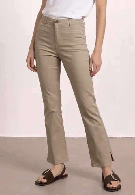 Pantalon beige taille haute fendu en bas, t-shirt blanc rentré et sandales marron.