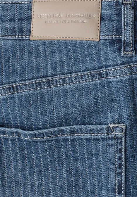 Detailaufnahme einer blauen Jeans-Tasche mit Streifenmuster und Lederlabel.