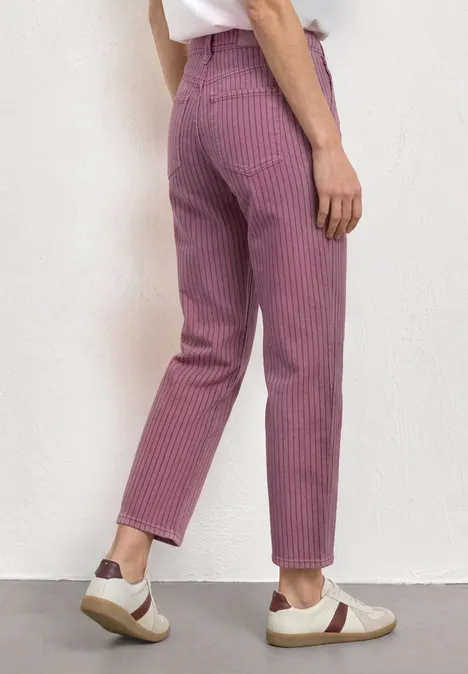 Person trägt hauchzart gestreifte, violette Hose und weiße Sneaker, Blick von hinten.