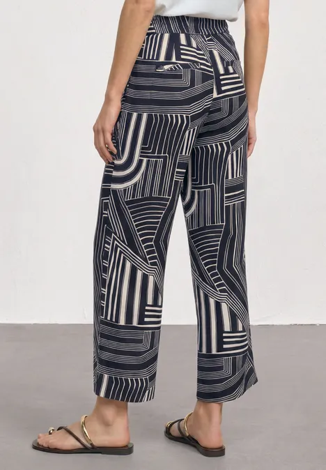 High Waist Culotte mit Muster darkest blue Weite Hose mit abstraktem Schwarz-Beige-Streifenmuster und goldenen Riemchensandalen.