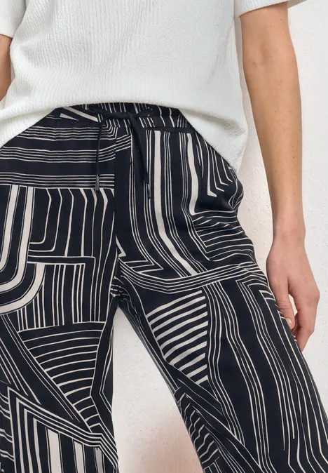 High Waist Culotte mit Muster darkest blue Person trägt weißen Pullover und schwarz-weiße Hosen mit abstraktem Streifenmuster.