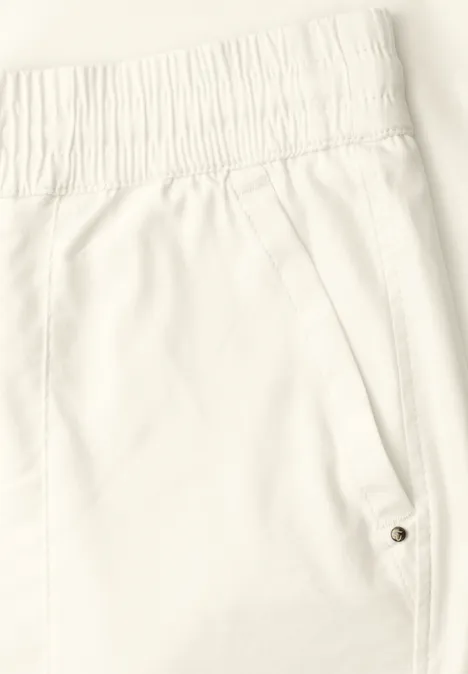 Nahaufnahme einer weißen Hose mit elastischem Bund und seitlicher Tasche mit Druckknopf.