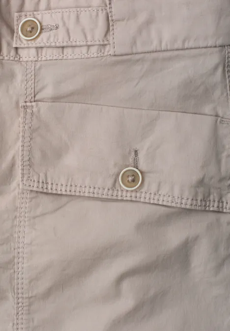 Nahaufnahme einer hellbeigen Stofftasche mit Knopfverschluss und sichtbaren Nähten.