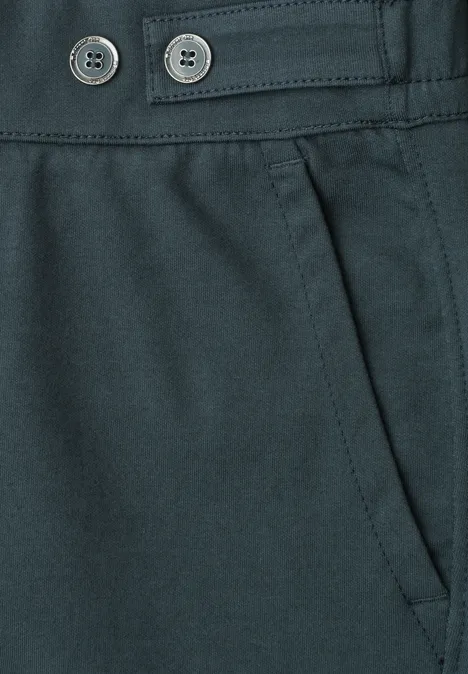 Nahaufnahme einer dunklen Hose mit Schrägtasche und zwei Zierknöpfen am Bund.