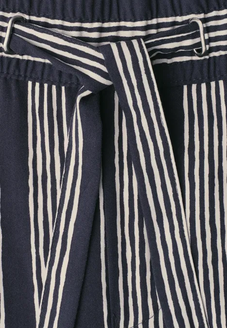 Pantalon bleu marine à rayures blanches verticales avec ceinture assortie.