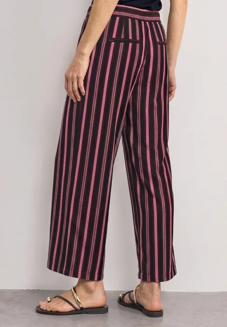 Damenhose, weite Beine, schwarz-rot gestreift, hohe Taille, knöchellang, mit Sandalen kombiniert.