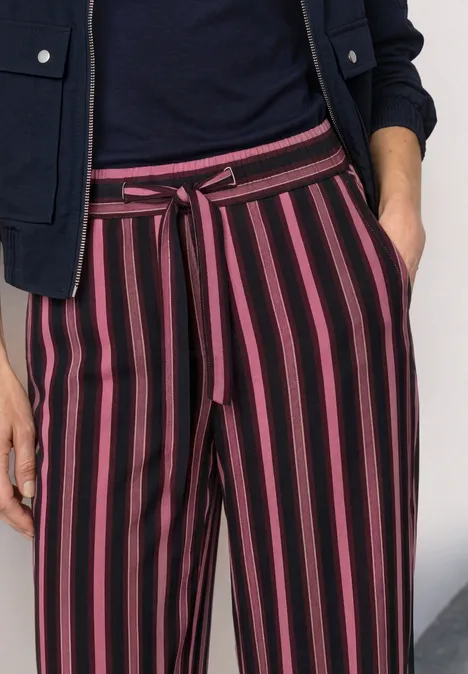 Gestreifte Hose mit schwarzen und pinken Längsstreifen und Stoffgürtel.