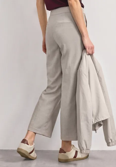 High Waist Culotte met gespdetails clay sand Model draagt wijde grijze broek, houdt bijpassend colbert vast en combineert dit met plateau-sneakers.