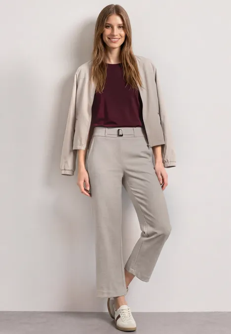 High Waist Culotte met gespdetails clay sand Vrouw in beige cropped broek met bijpassend jasje over de schouders, bordeaux top en witte sneakers.