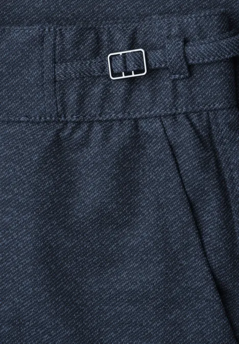 Nahaufnahme einer dunkelblauen Stoffhose mit zierlichem Metall-Schließer und Falten.