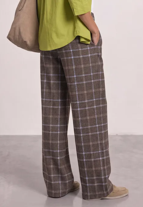 Wide Leg Velorus Hose im Casual Fit silk brown Hose mit braunem Karomuster, weites Bein, kombiniert mit grünem Overshirt, Beuteltasche und beigen Schuhen.