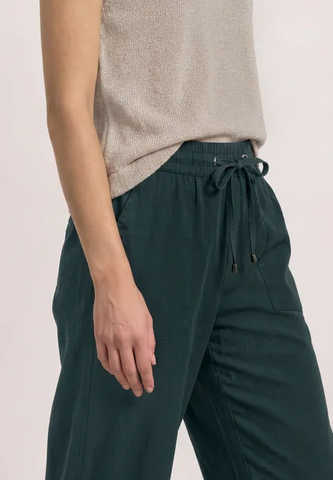 Personne porte un pantalon vert foncé en lin à taille élastiquée et coupe droite.