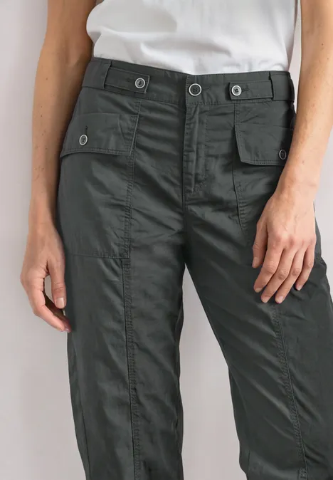 Untere Körperpartie mit grauer Cargohose mit aufgesetzten Taschen und weißem Shirt, Hände locker an den Seiten.