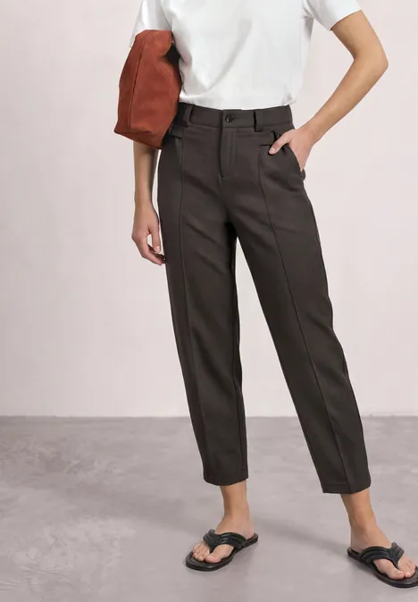 High Waist Barrel Leg Hose im Casual Fit black coffee Frau in weißem T-Shirt, dunklen, hoch taillierten Hosen und Flip-Flops, trägt rote Tasche