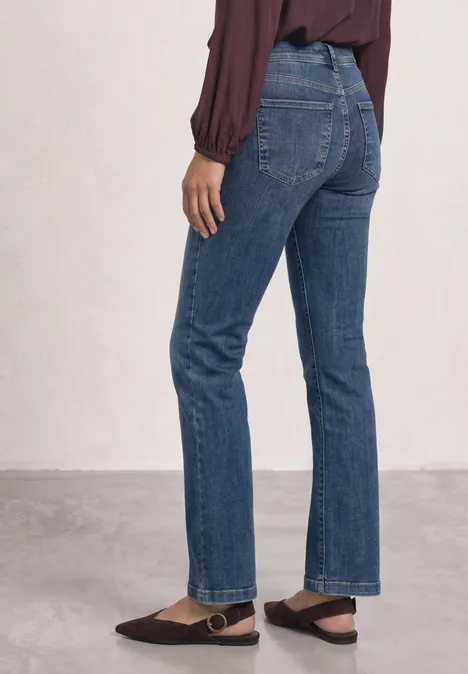 Mid Waist Bootcut Jeans im Slim Fit Medium Blue Random Washed Eine Person trägt gerade geschnittene blaue Jeans und eine burgunderrote Bluse.