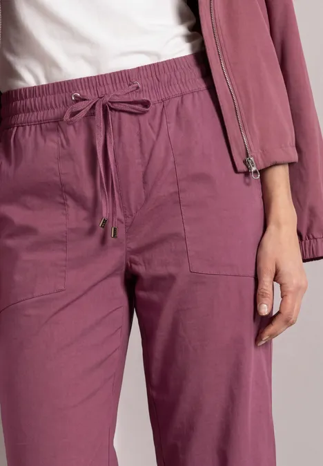 Nahaufnahme von pinken, locker sitzenden Jogginghosen mit Kordelzug und aufgesetzten Taschen.