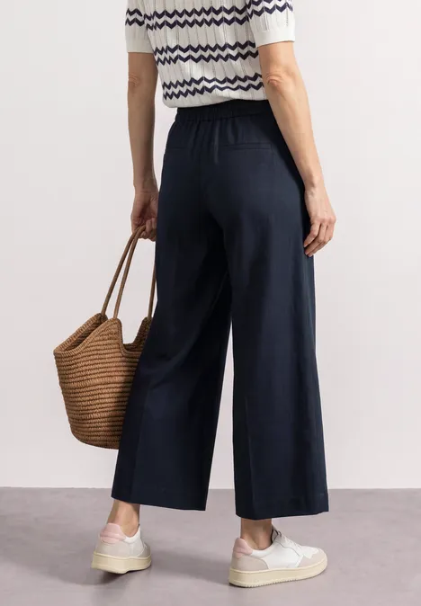 Pantalon Straight Leg et décontracté, avec revers darkest blue Personne porte une jupe-culotte bleu marine, un top rayé, des baskets blanches et un panier en osier.