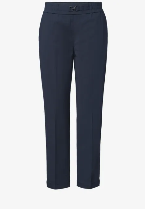 Dunkelblaue, schmale Hose mit geradem Bein, Bundfalten und Knopf- sowie Reißverschluss.