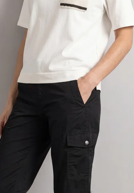 Person porte un T-shirt blanc et un pantalon cargo noir avec poches.