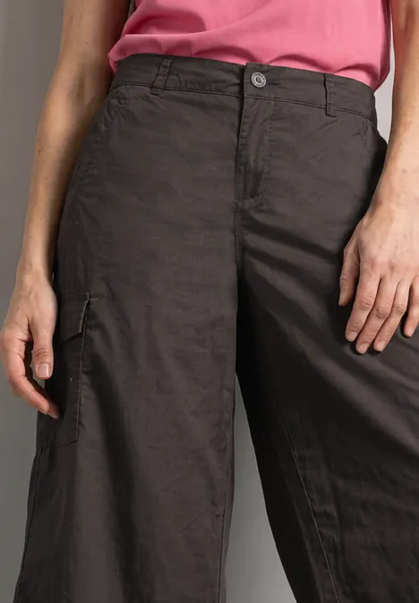 Une personne porte un pantalon cargo noir ample et un top rose.