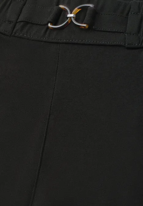 Schwarze Hose mit elastischem Bund und dekorativem Gürtel mit goldenen Ringen.