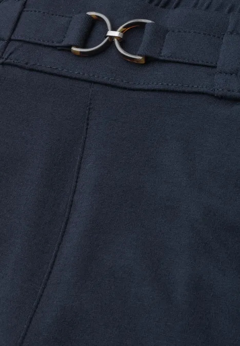 Donkerblauwe pantalon van stof met hoge taille, afgezet met een smalle riem en een goudkleurige dubbele gesp.