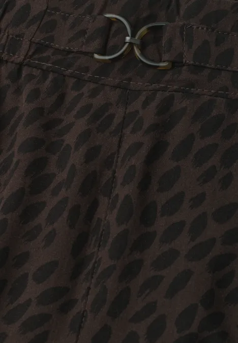 Mid Waist Straight Leg Hose mit Print molten earth Nahaufnahme eines braunen Stoffes mit schwarzem Blattmuster und dekorativem Metallgürtel mit verschlungenen Ringen.