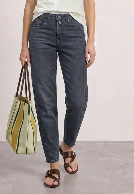 High Waist Barrel Leg Jeans im Loose Fit Steel Grey Washed Person trägt dunkle Jeans, helles Shirt, braune Sandalen und hält gestreifte Strandtasche.