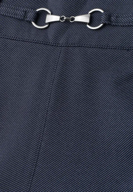 Donkerblauw gestructureerd textiel met een zilverkleurig bitachtig metalen sierstuk.