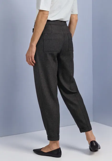 Barrel Leg Hose mit Schnallendetail black coffee Rückenansicht einer Person mit dunkelgrauen, hoch taillierten, schmal zulaufenden Anzughosen und schwarzen Slippern.