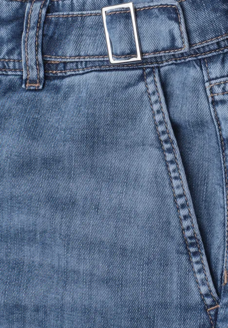 Jean taille moyenne à jambes larges, coupe ample mid blue washed Nahaufnahme einer blauen Jeanshose mit Hosentasche, Bund und Gürtel mit silberner Schnalle.