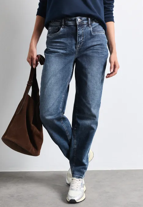 Jeans met High Waist en wijd uitlopende pijpen in een Loose Fit-pasvorm Medium Blue Random Washed Persoon draagt blauwe jeans, witte sneakers en houdt een bruine tas vast.