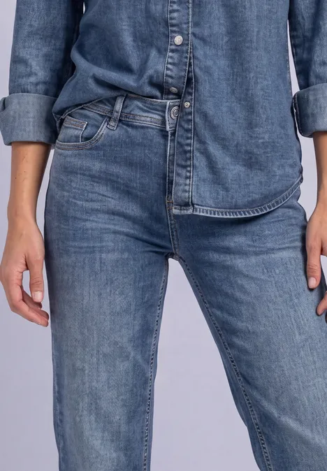 Jeans z prostymi nogawkami i guzikowymi detalami Medium Blue Random Washed Zbliżenie osoby w ciemnoniebieskiej koszuli i spodniach dżinsowych, ręce swobodnie ułożone wzdłuż ciała.