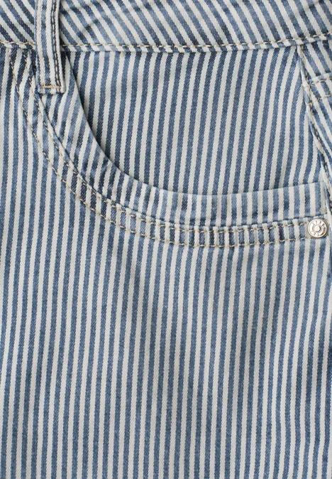 Close-up van een blauw-wit gestreepte denim zak met zilverkleurige klinknagel en sierstiksels.